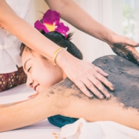 Therapist is scrubbing Charcoal clay scrub cream on women back